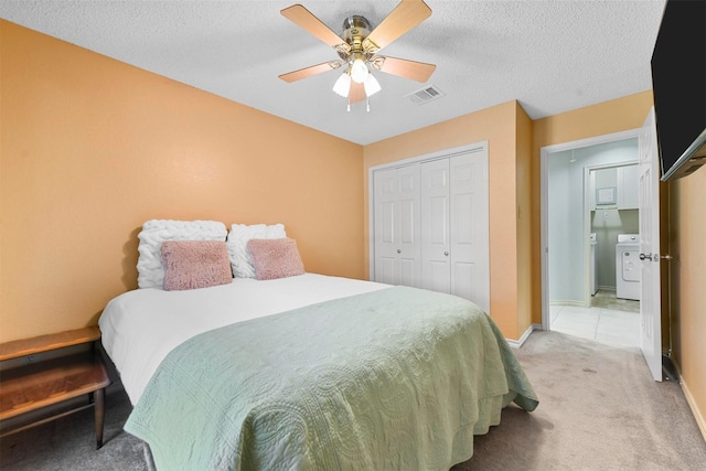 carpeted bedroom featuring washer / clothes dryer, ceiling fan, a closet, and a textured ceiling