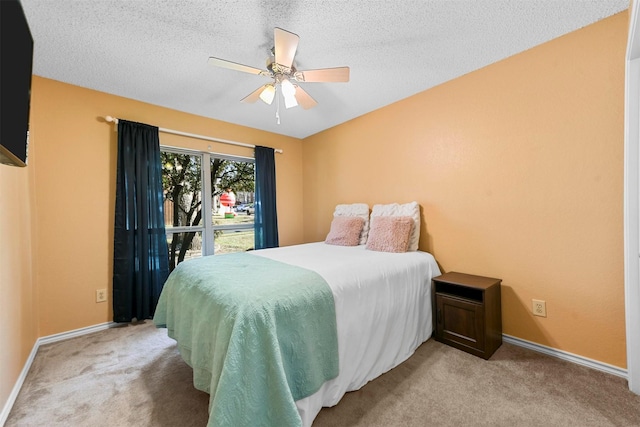 bedroom featuring ceiling fan, light colored carpet, and a textured ceiling