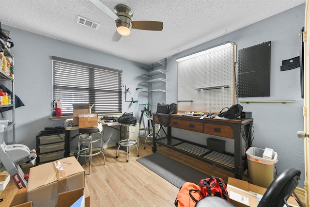 office featuring ceiling fan, light wood-type flooring, and a textured ceiling