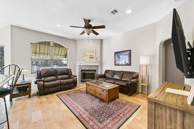 living room with light wood-type flooring, a textured ceiling, and ceiling fan