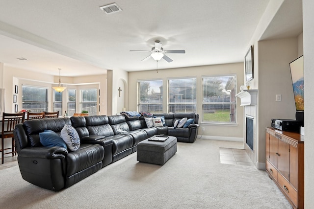 living room with a fireplace, light colored carpet, and ceiling fan