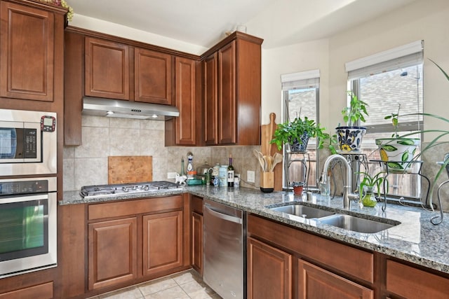 kitchen with sink, appliances with stainless steel finishes, tasteful backsplash, stone countertops, and light tile patterned flooring