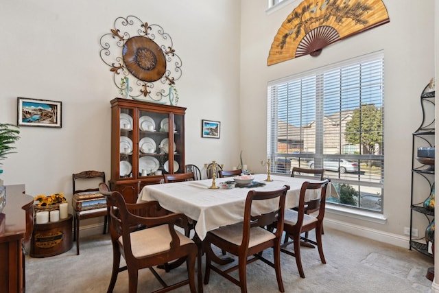 carpeted dining area featuring a towering ceiling