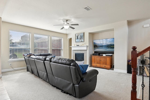 carpeted living room with ceiling fan and a tiled fireplace