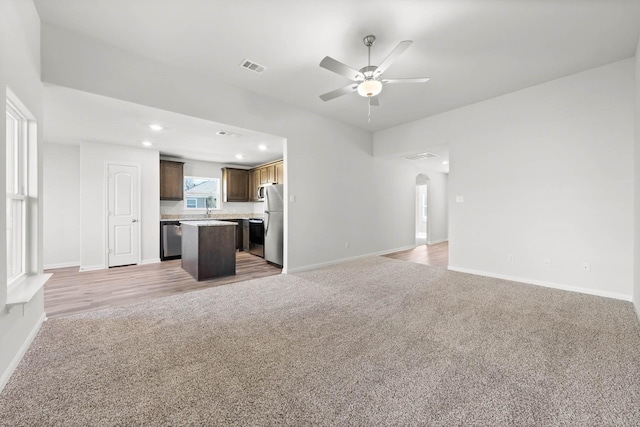 unfurnished living room featuring ceiling fan, sink, and carpet floors