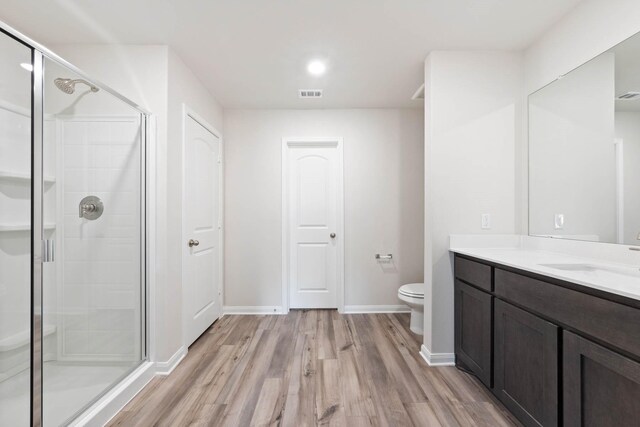 bathroom featuring hardwood / wood-style floors, vanity, toilet, and walk in shower