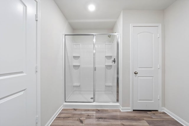 bathroom with hardwood / wood-style floors and a shower with shower door