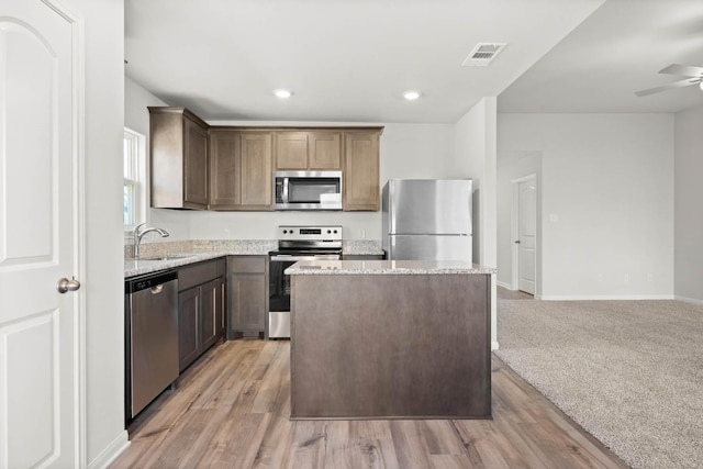 kitchen featuring sink, light hardwood / wood-style flooring, ceiling fan, appliances with stainless steel finishes, and a center island