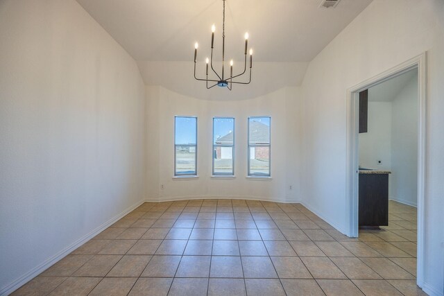 tiled spare room with an inviting chandelier