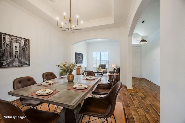 dining room with a raised ceiling, ornamental molding, dark hardwood / wood-style floors, and an inviting chandelier