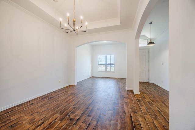 empty room featuring a raised ceiling, crown molding, and an inviting chandelier