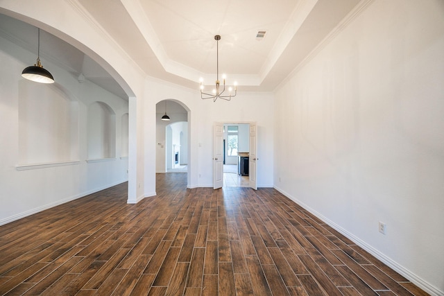 unfurnished dining area with an inviting chandelier, a raised ceiling, and ornamental molding