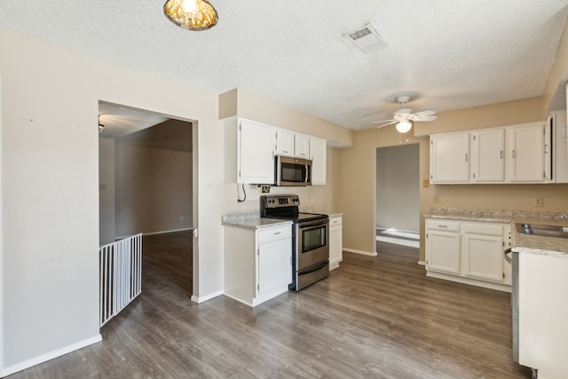 kitchen featuring a textured ceiling, dark hardwood / wood-style floors, white cabinetry, and stainless steel appliances