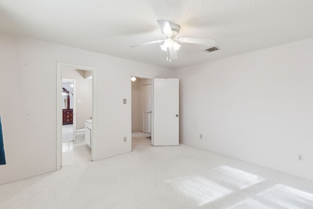 unfurnished bedroom with ceiling fan, light carpet, and connected bathroom