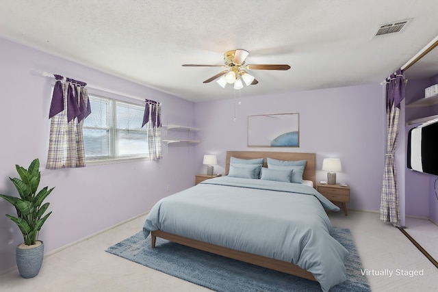 bedroom featuring carpet, ceiling fan, and a textured ceiling