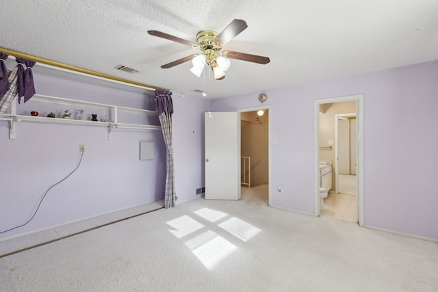 unfurnished bedroom featuring ceiling fan, a closet, ensuite bathroom, and light colored carpet