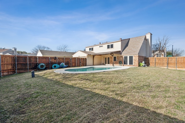 back of property with a fenced in pool and a yard