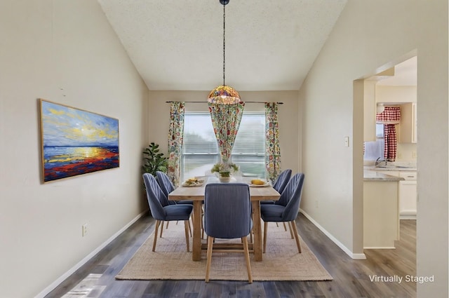 dining space featuring vaulted ceiling, dark hardwood / wood-style floors, and a textured ceiling