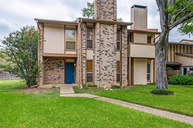 view of front of house featuring a balcony and a front yard