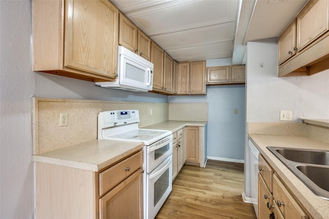 kitchen with sink, light brown cabinets, white appliances, and light hardwood / wood-style floors