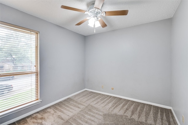 spare room with ceiling fan, plenty of natural light, carpet, and a textured ceiling