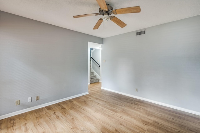 spare room with a textured ceiling, light wood-type flooring, and ceiling fan