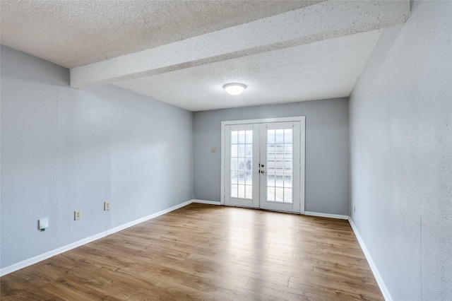 spare room featuring french doors, a textured ceiling, and light wood-type flooring