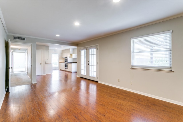 unfurnished living room with a wealth of natural light, french doors, and crown molding