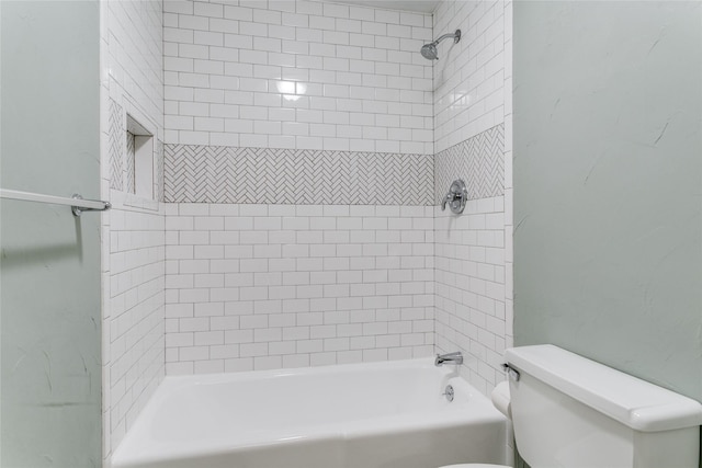 bathroom featuring tiled shower / bath combo and toilet