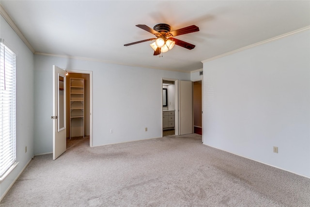 unfurnished bedroom with carpet flooring, a walk in closet, ensuite bath, and ceiling fan