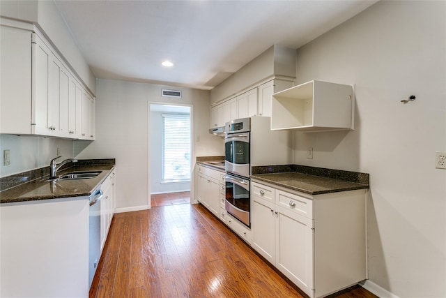 kitchen featuring stainless steel appliances, sink, dark stone countertops, hardwood / wood-style floors, and white cabinetry