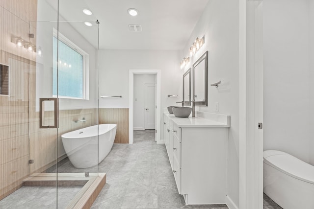 full bathroom featuring toilet, vanity, separate shower and tub, and tile walls