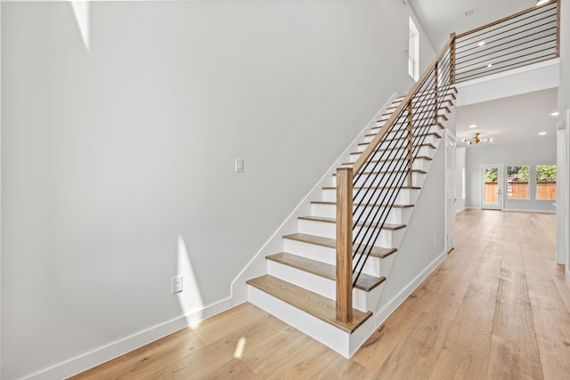 staircase with a towering ceiling and wood-type flooring