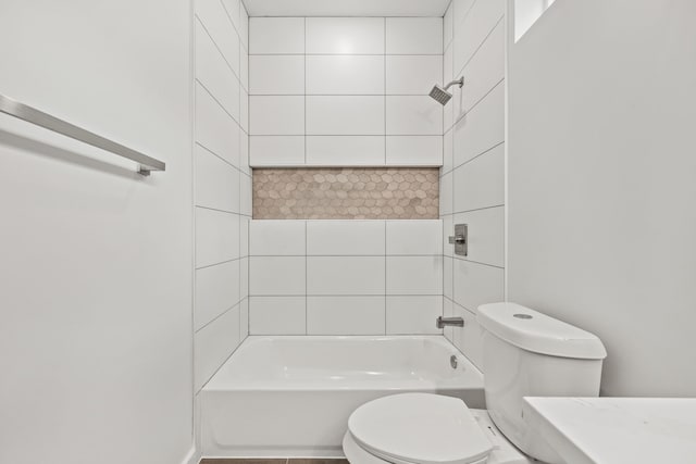 bathroom featuring tiled shower / bath combo and toilet