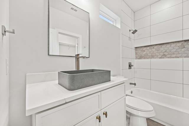 full bathroom with vanity, tiled shower / bath combo, and toilet