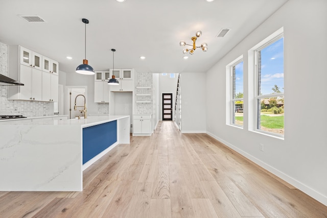 kitchen featuring black gas cooktop, decorative backsplash, light wood-type flooring, decorative light fixtures, and white cabinetry