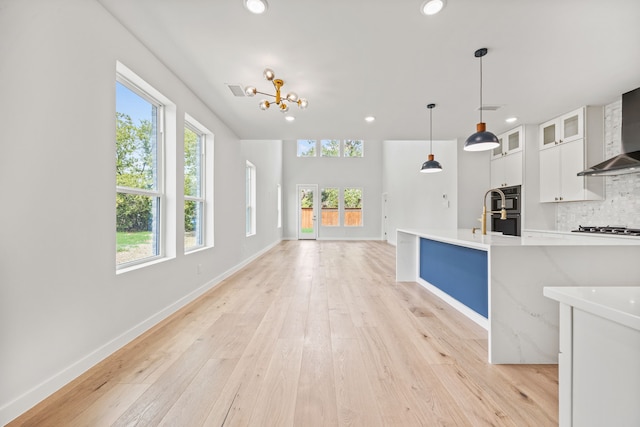 kitchen with white cabinetry, an inviting chandelier, tasteful backsplash, light hardwood / wood-style flooring, and decorative light fixtures