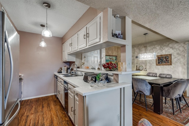 kitchen featuring pendant lighting, white cabinets, sink, stainless steel fridge, and kitchen peninsula