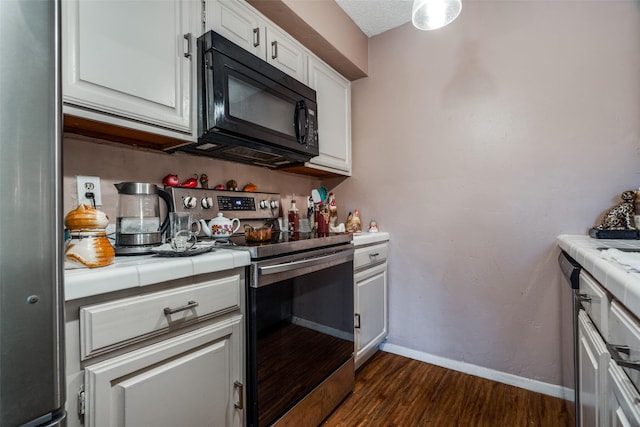 kitchen featuring dark wood-type flooring, tile countertops, a textured ceiling, white cabinets, and appliances with stainless steel finishes