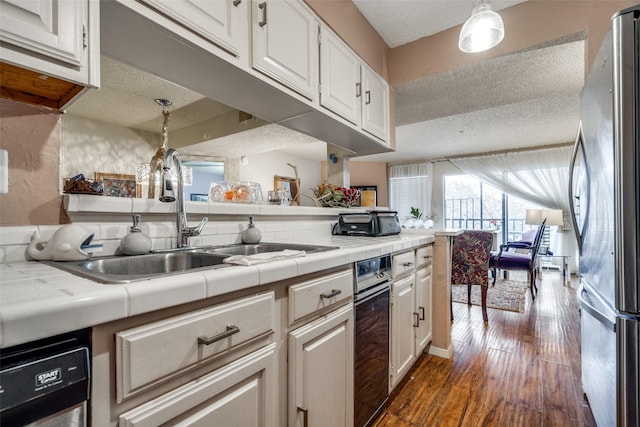 kitchen featuring decorative light fixtures, white cabinetry, a textured ceiling, and stainless steel refrigerator