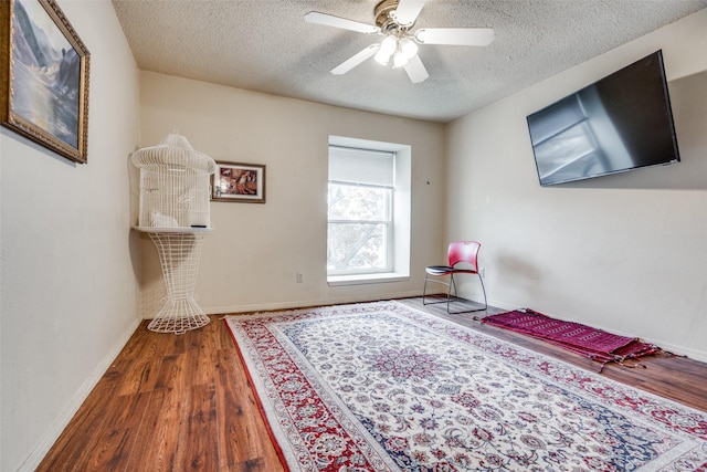 bedroom featuring ceiling fan, dark hardwood / wood-style flooring, and a textured ceiling