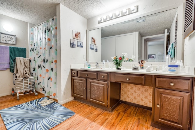 bathroom with vanity, wood-type flooring, a textured ceiling, and walk in shower