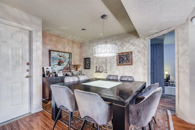 dining area featuring a chandelier, a textured ceiling, and hardwood / wood-style flooring