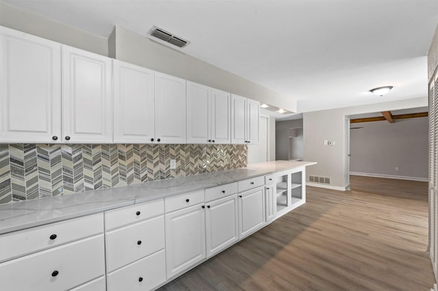 kitchen with backsplash, light stone countertops, white cabinets, and hardwood / wood-style flooring