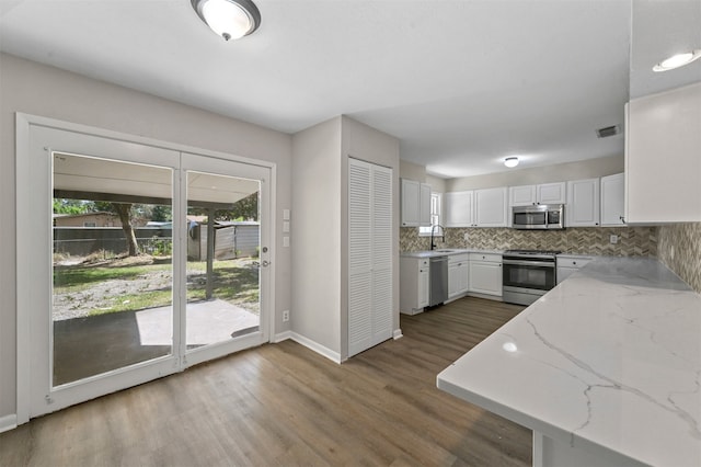 kitchen with sink, decorative backsplash, light stone countertops, appliances with stainless steel finishes, and white cabinetry