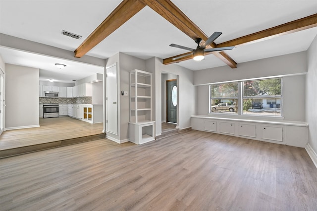 unfurnished living room with ceiling fan, beamed ceiling, and light wood-type flooring