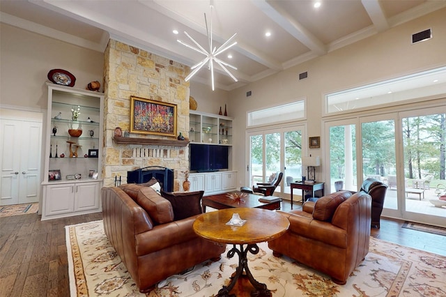 living room with crown molding, beam ceiling, a towering ceiling, a stone fireplace, and light wood-type flooring