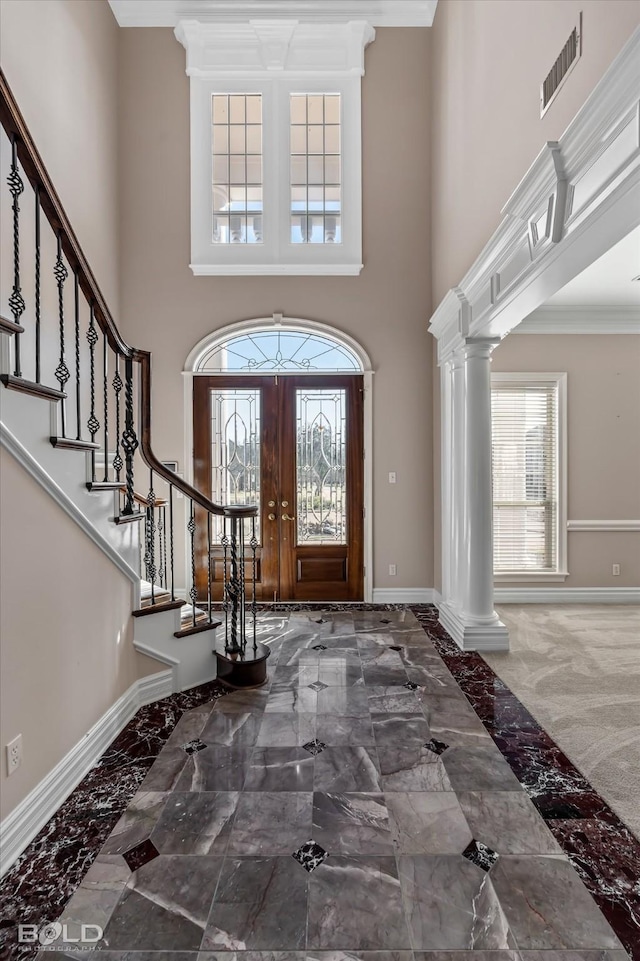 foyer featuring ornamental molding, decorative columns, a healthy amount of sunlight, and a high ceiling