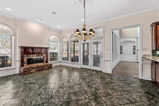 unfurnished living room with ornamental molding, plenty of natural light, a chandelier, and a brick fireplace