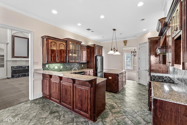 kitchen featuring stainless steel refrigerator, decorative light fixtures, sink, ornamental molding, and kitchen peninsula